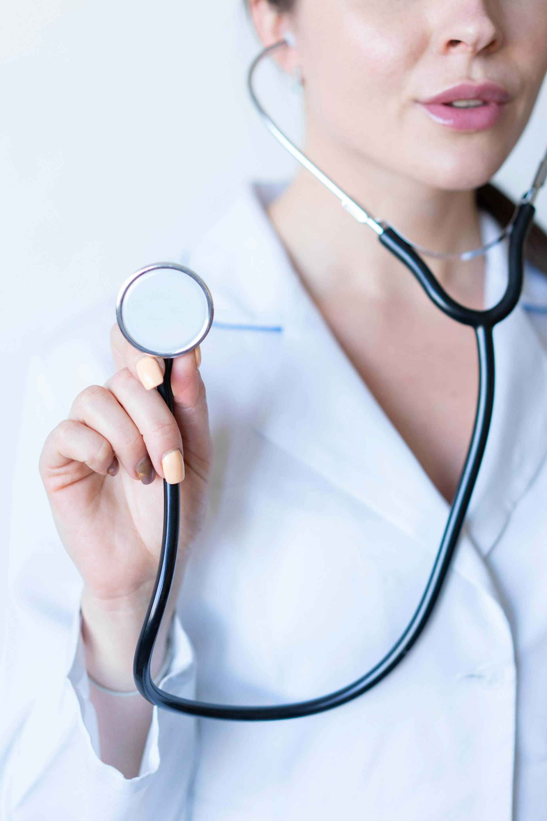 Médica de jaleco segurando o estetoscópio