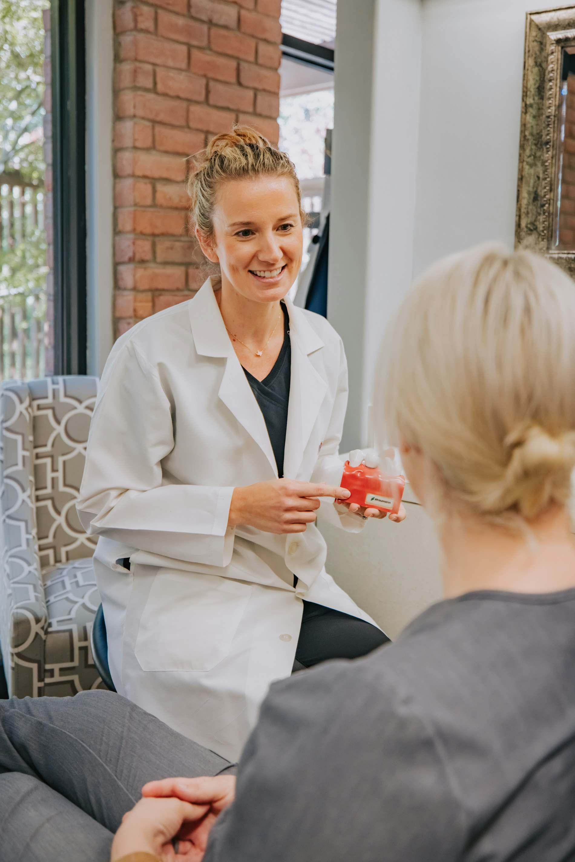 Médica de jaleco conversando com uma paciente no consultório