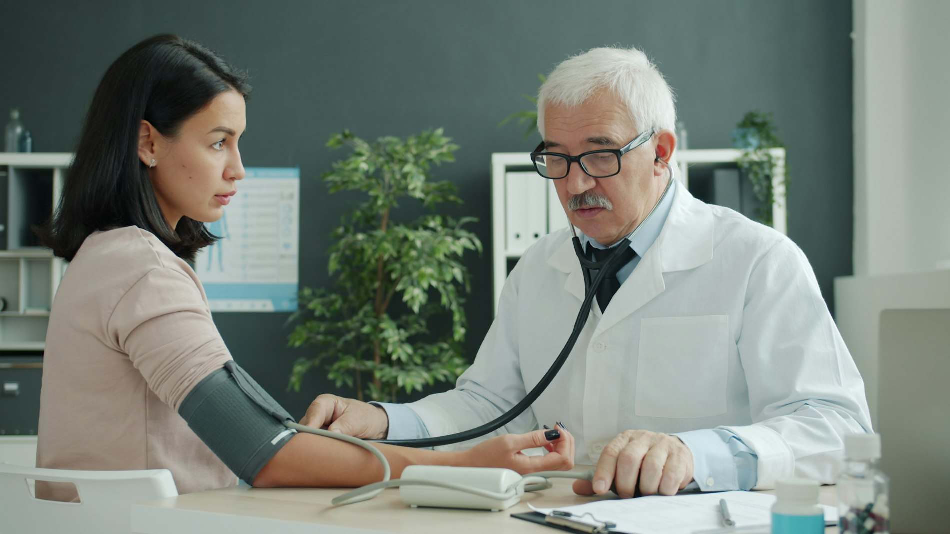 Médico medindo a pressão arterial de uma paciente no consultório